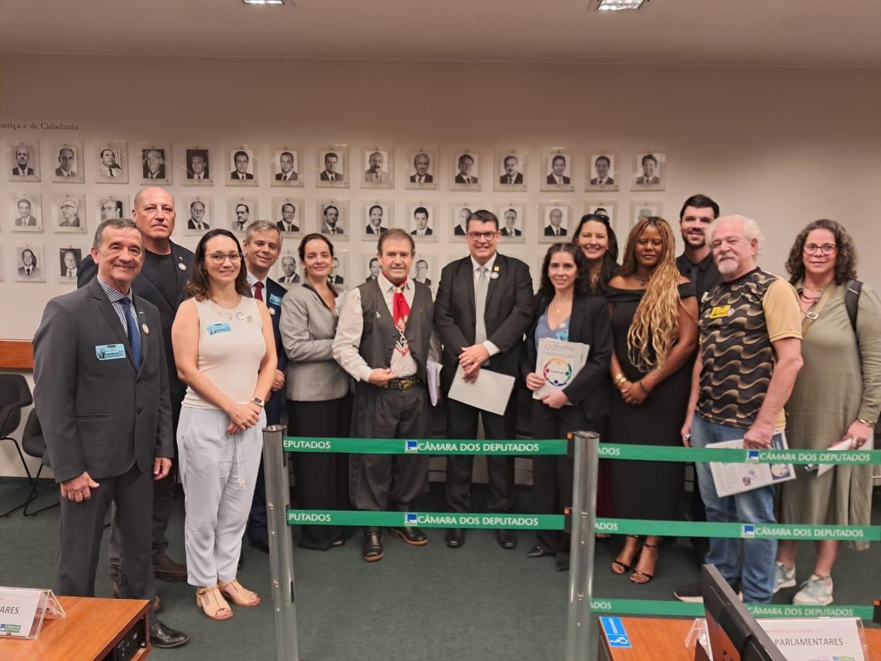 Pessoas em pé lado a lado, posando para foto com o deputado federal, Pompeo de Mattos.