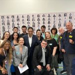 Pessoas reunidas em mural posando para a foto.
