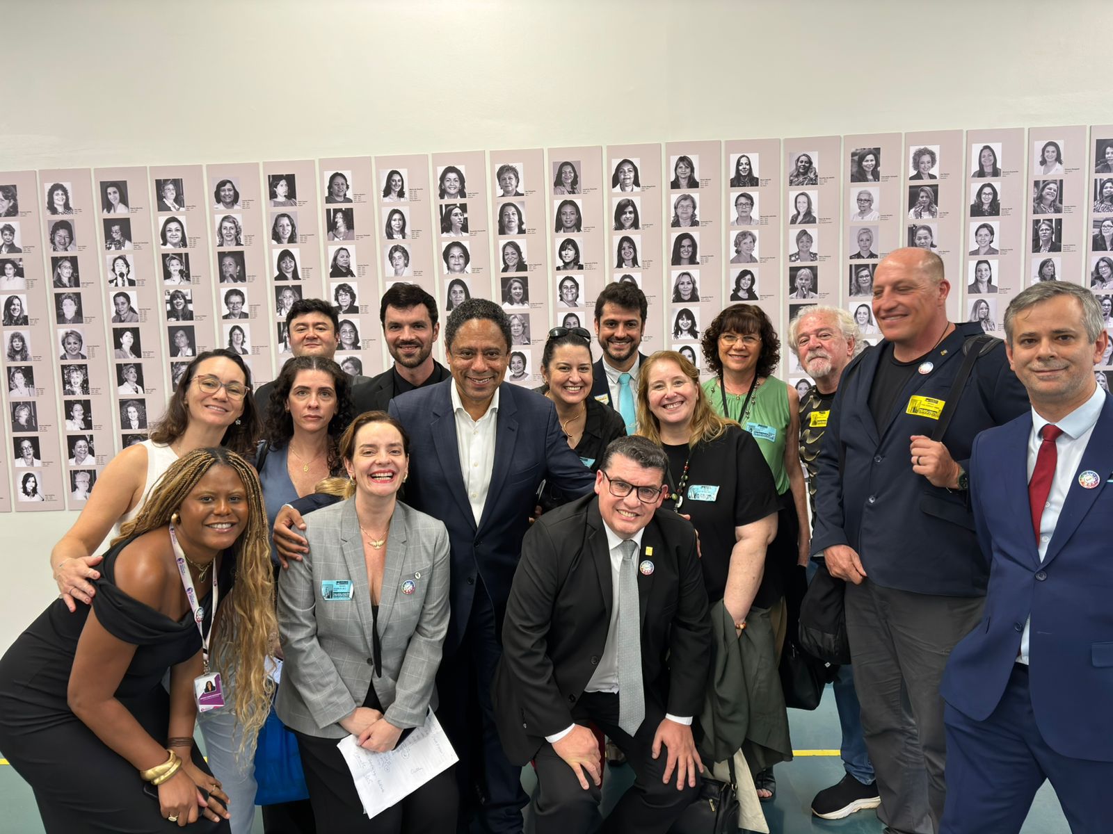 Pessoas reunidas em mural posando para a foto.