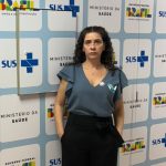 Mulher de cabelos pretos e cacheados, vestindo camiseta azul e calça preta. Essa é a vice-presidente do CRMV-SP Carolina Saraiva Filippos de Toledo a frente do gabinete do ministro.