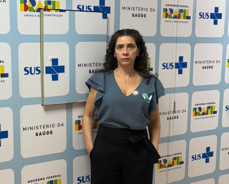 Mulher de cabelos pretos e cacheados, vestindo camiseta azul e calça preta. Essa é a vice-presidente do CRMV-SP Carolina Saraiva Filippos de Toledo a frente do gabinete do ministro.