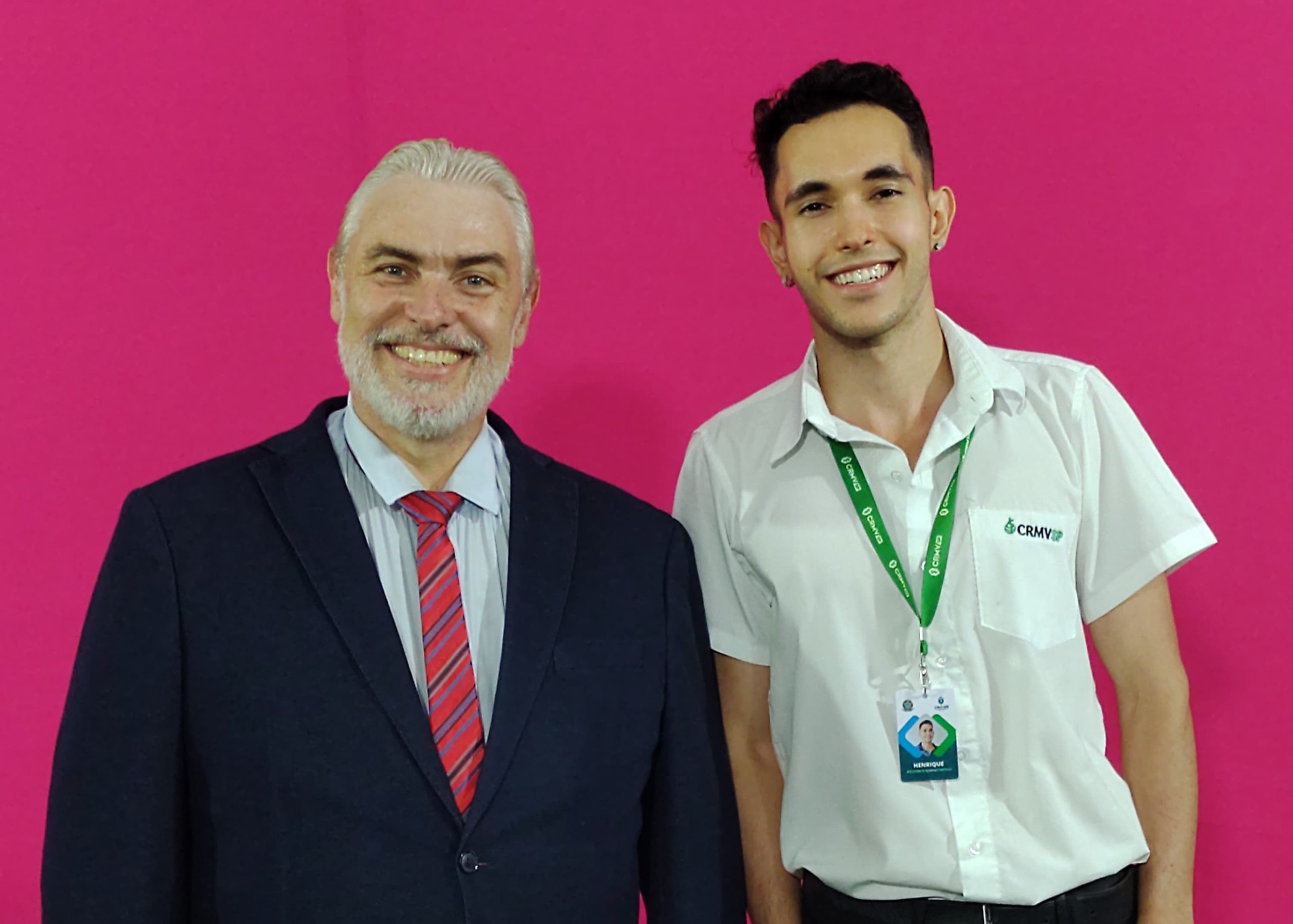 Da esquerda para a direita: homem com cabelo e barba branca e está terno e gravata vermelha, o da direita está com o uniforme do CRMV-SP cabelos curtos e preto.