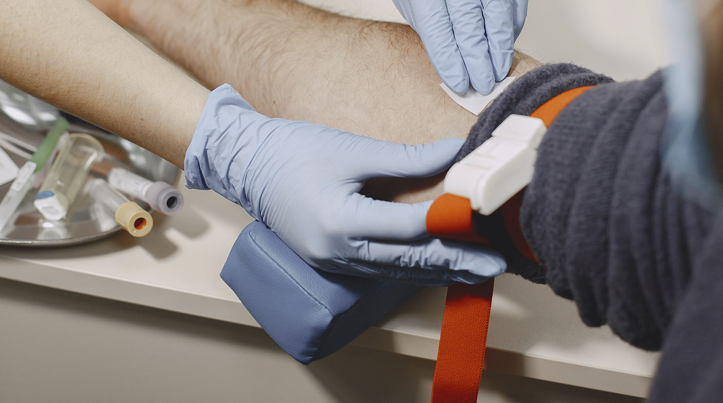 Braço masculino sendo preparado para retirada de sangue.