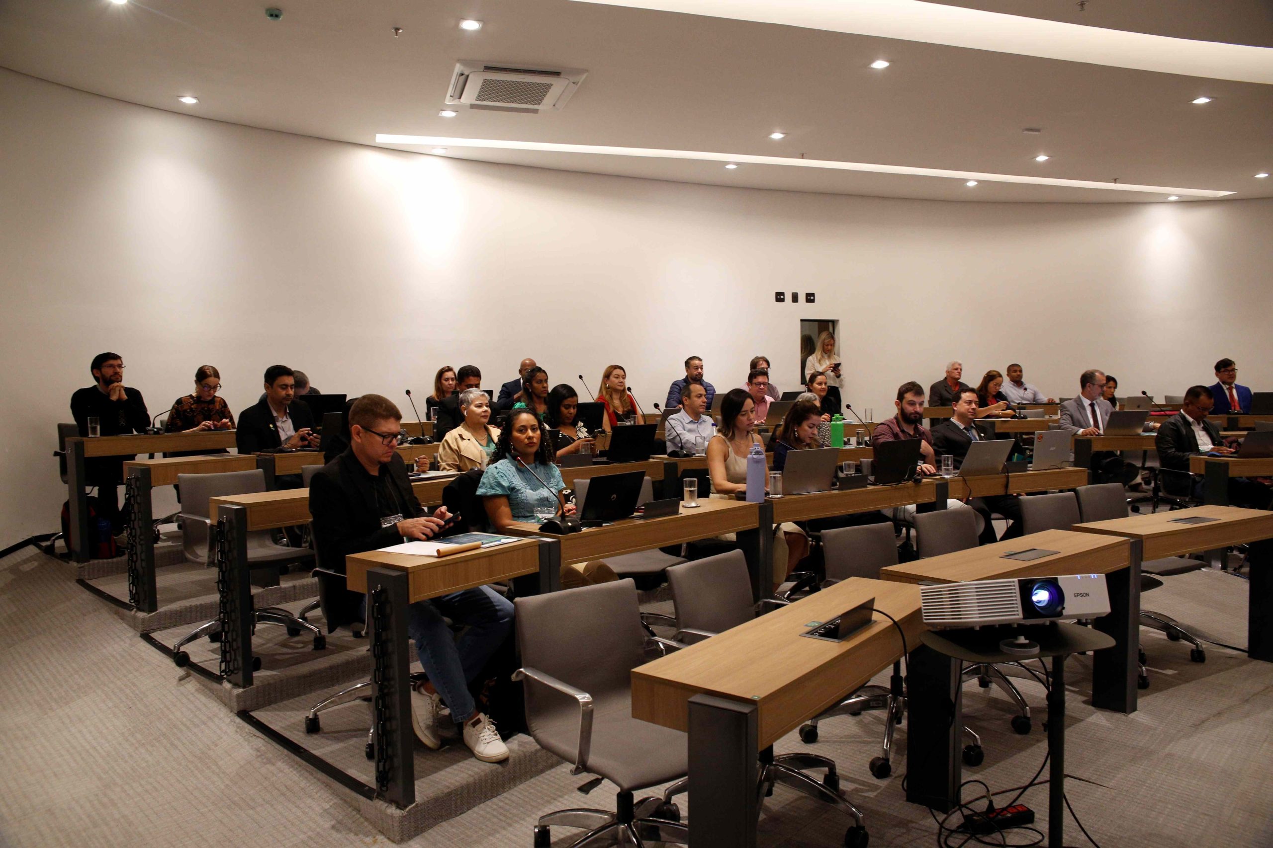 Visão lateral de todos os participantes do encontro sentados frente ao palco.