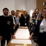 Pessoas em frente umas as outras em uma mesa posando para foto.