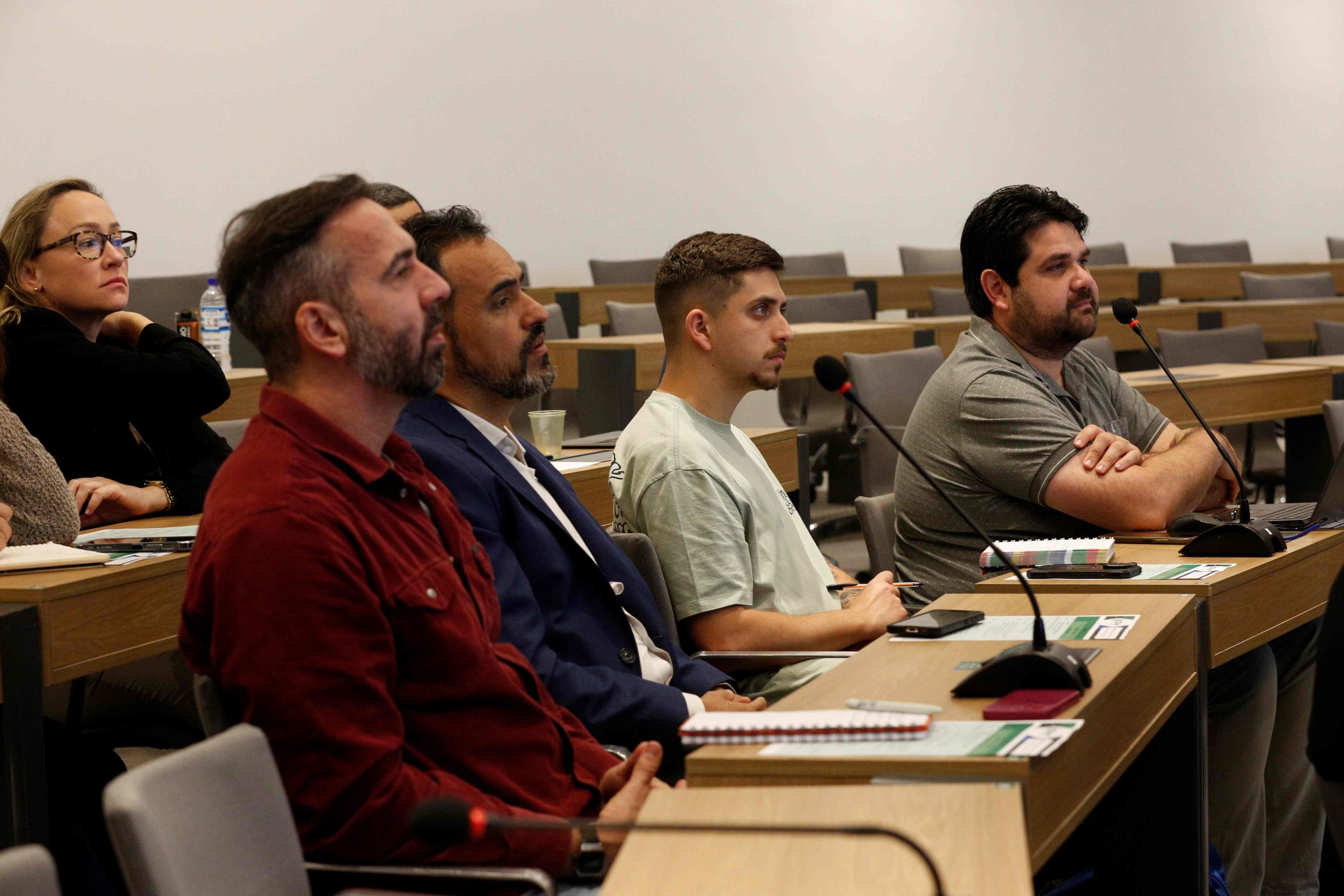 Pessoas sentadas a mesa assistindo a uma apresentação.