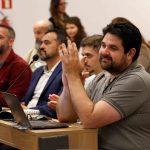 Pessoas sentadas assistindo a apresentação. Em destaque: Fabrício Braga Rassy.