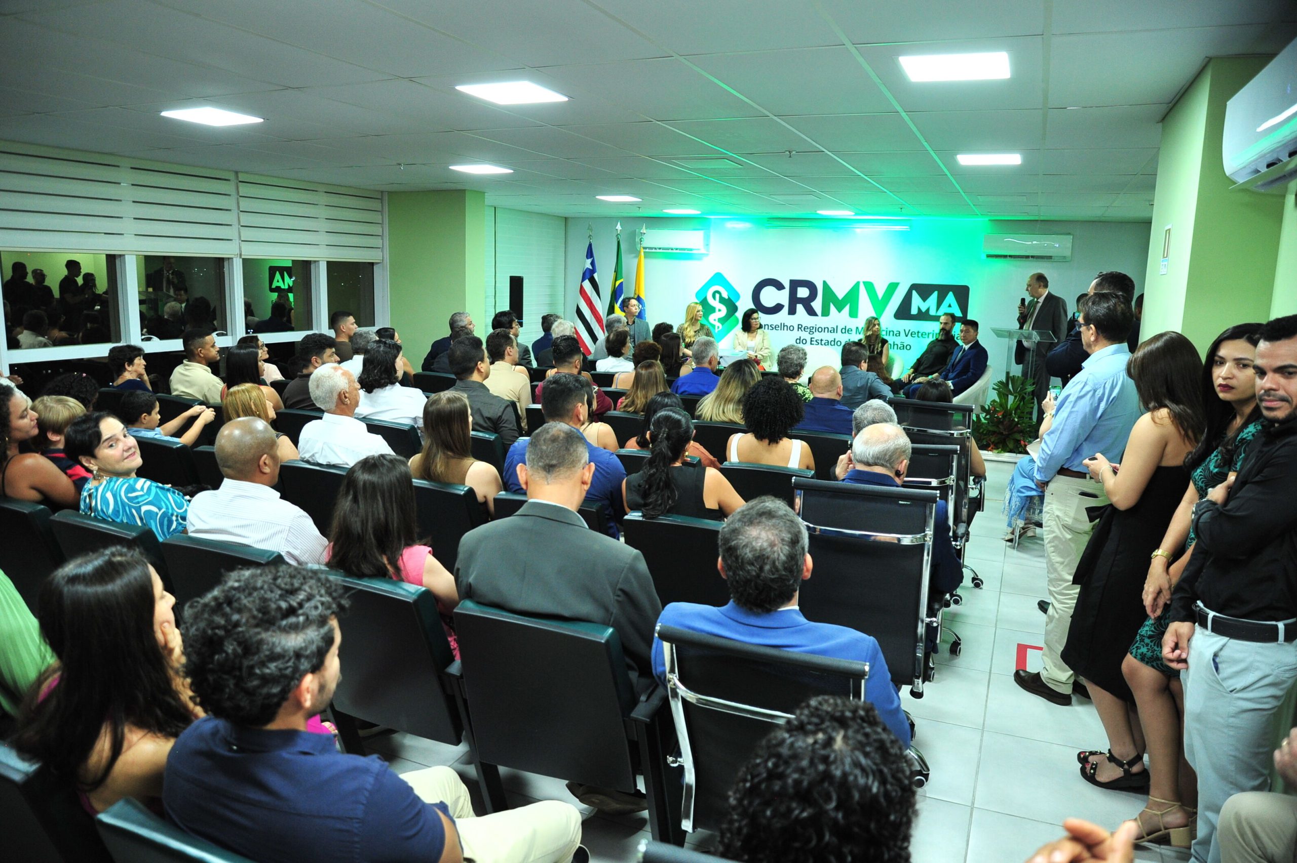 Fundo de um auditório cheio, à direita, há pessoas em pé e na frente membros da nova Diretoria do CRMV-MA.
