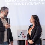 Homem em pé de blazer com microfone falando com a vice presidente do CRMV-SP, Carolina Filippos.