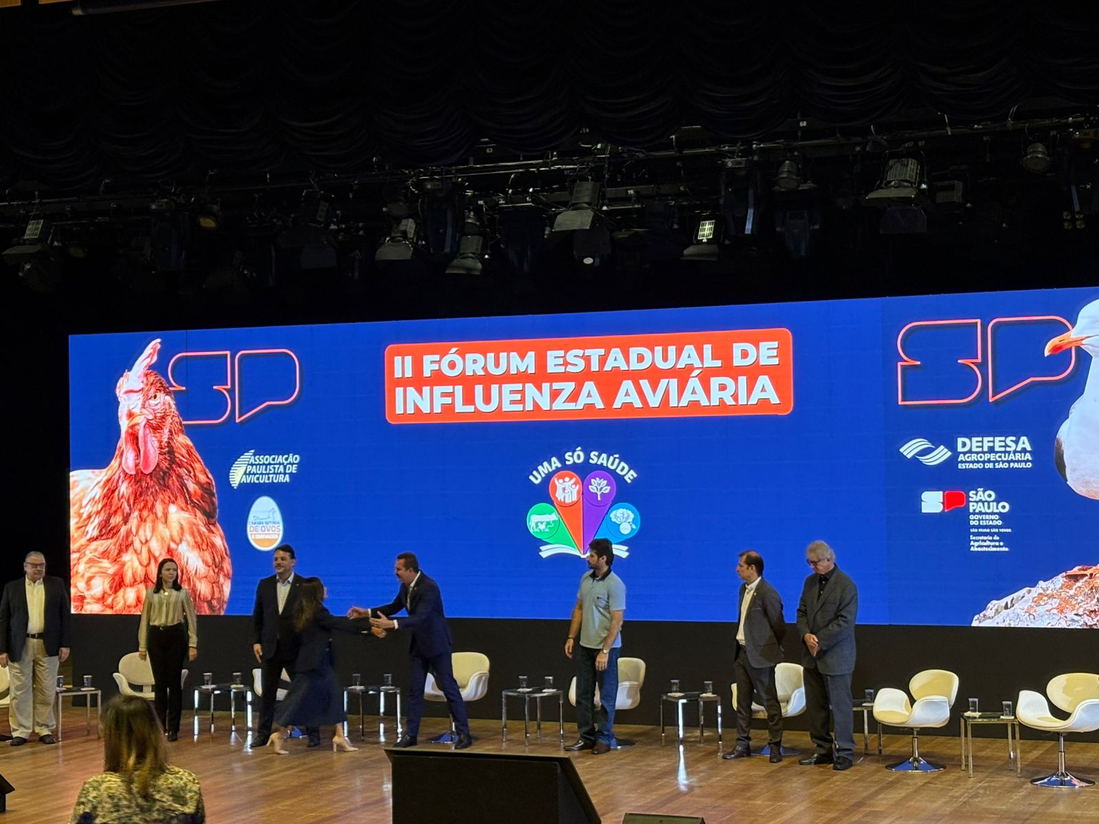 Pessoas reunidas no palco durante segundo fórum estadual de influenza aviária.