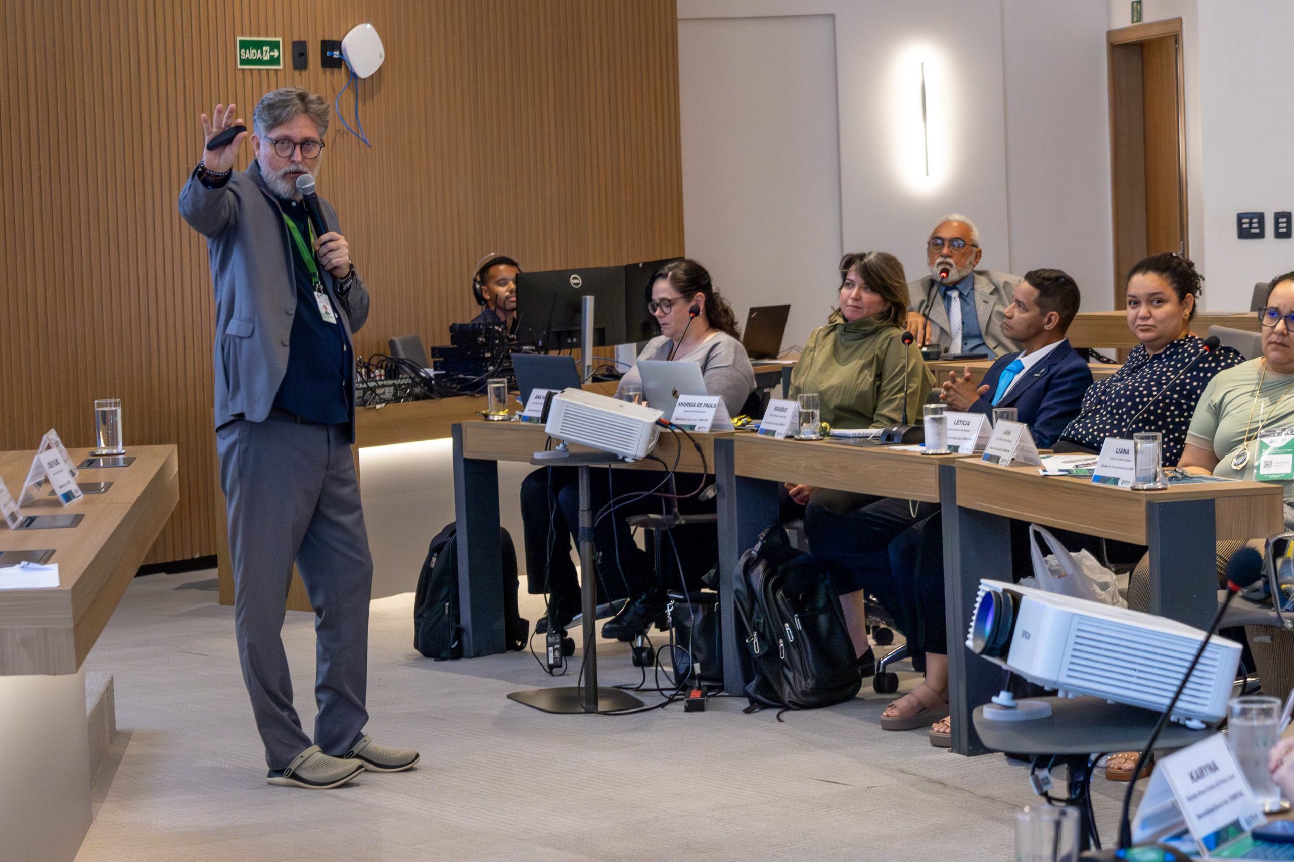 Homem palestrando a frente de participantes.