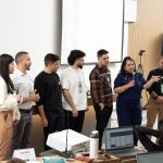 Pessoas reunidas frente ao telão realizando oficina.
