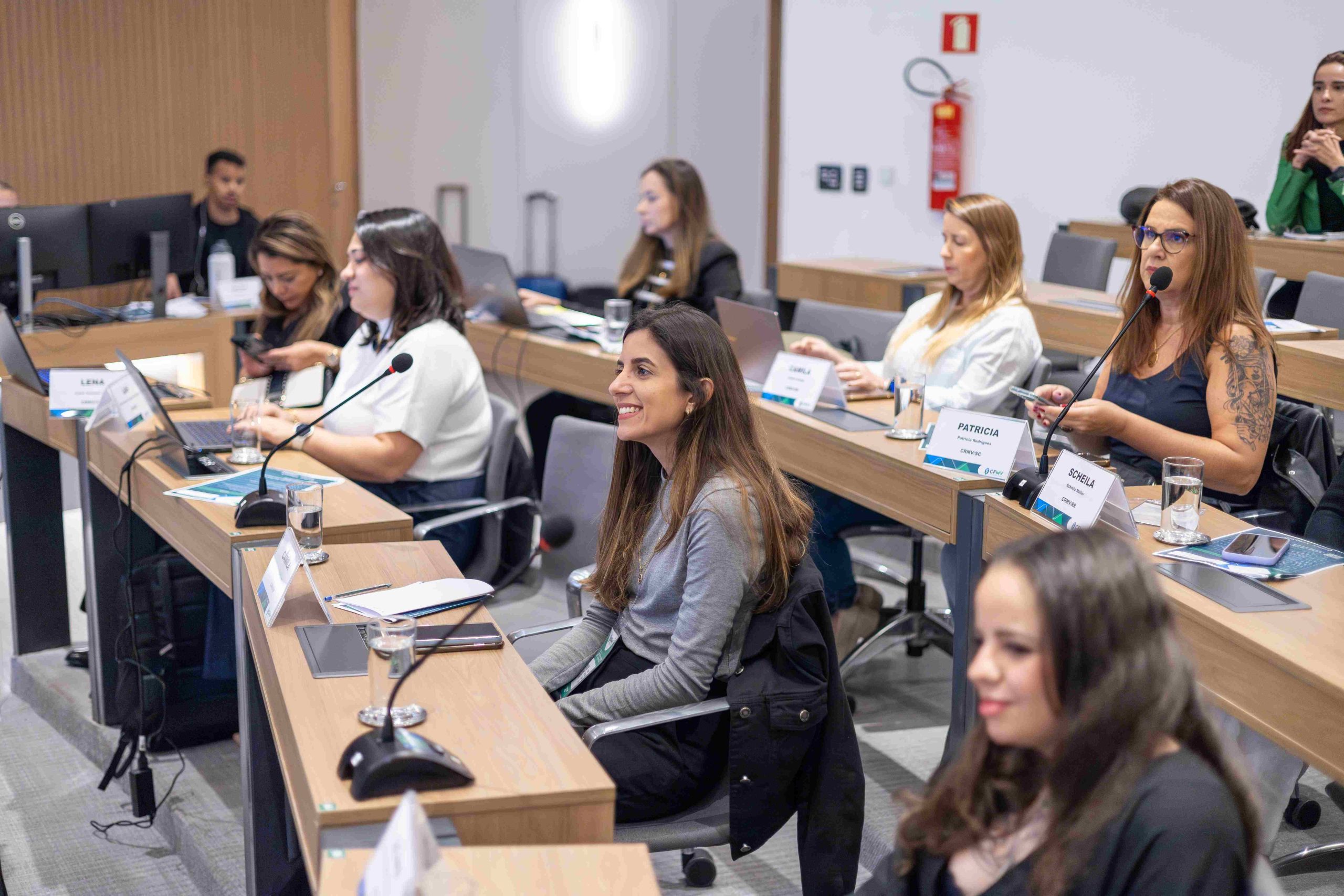 Pessoas sentadas a mesa olhando para o telão.