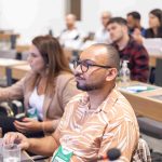 Homem careca, de óculos e barba usando o computador.