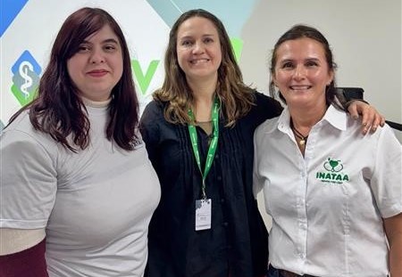 Três mulheres, no meio; a presidente do CRMV-SP, Daniela Pontes Chiebao, vestindo blusa azul marinho folgada com botões no meio entre duas mulheres de camisa branca representantes da Inataa.