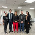 Membros da Diretoria pousando para foto com deputados da causa animal. Cinco pessoas de pé, sendo três mulheres e dois homens, em uma sala de reunião, sorrindo em sala de reunião com as bandeiras do estado de São Paulo, do Brasil e do CRMV-SP ao fundo, à esquerda.