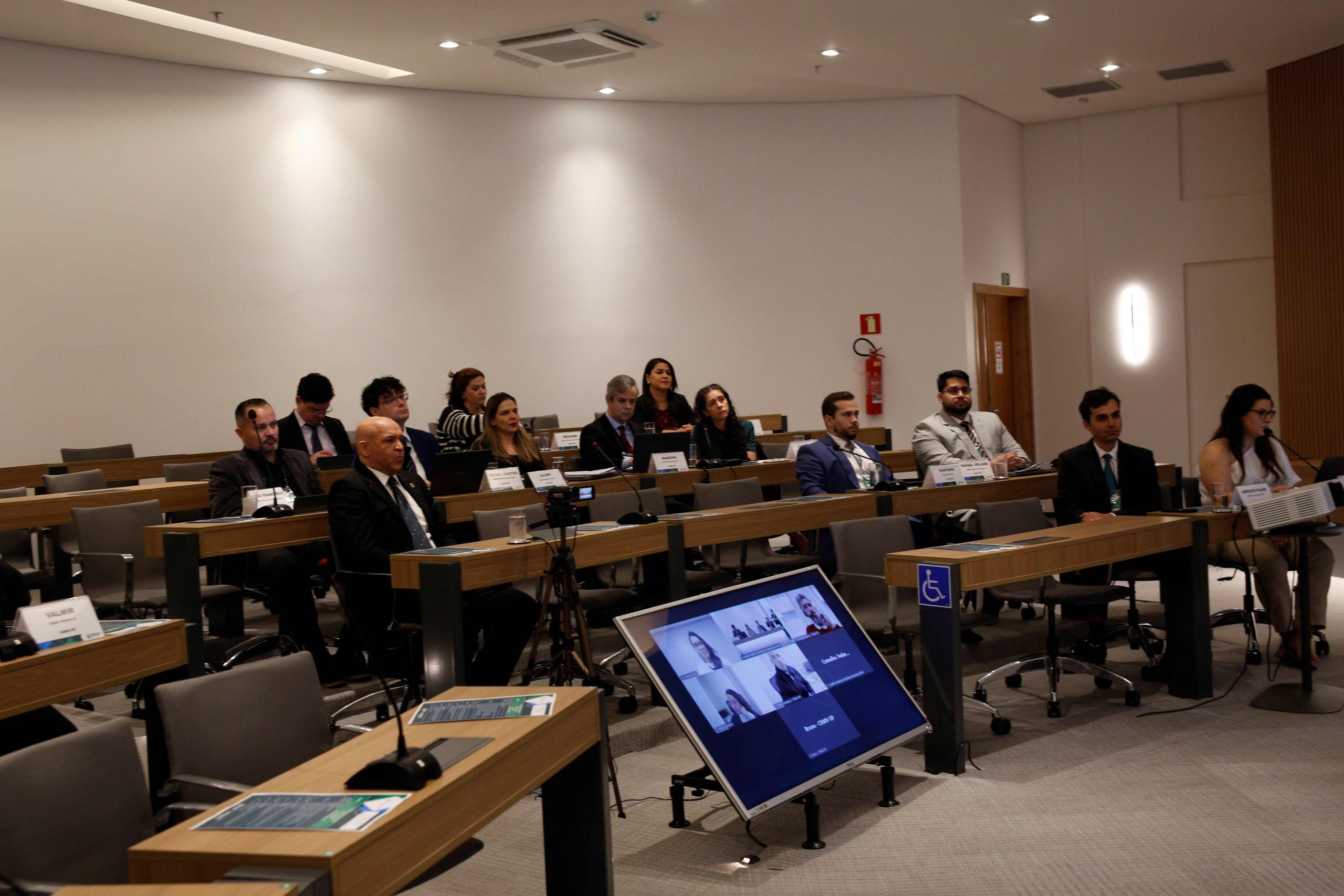 Pessoas sentadas à mesa frente ao palco.