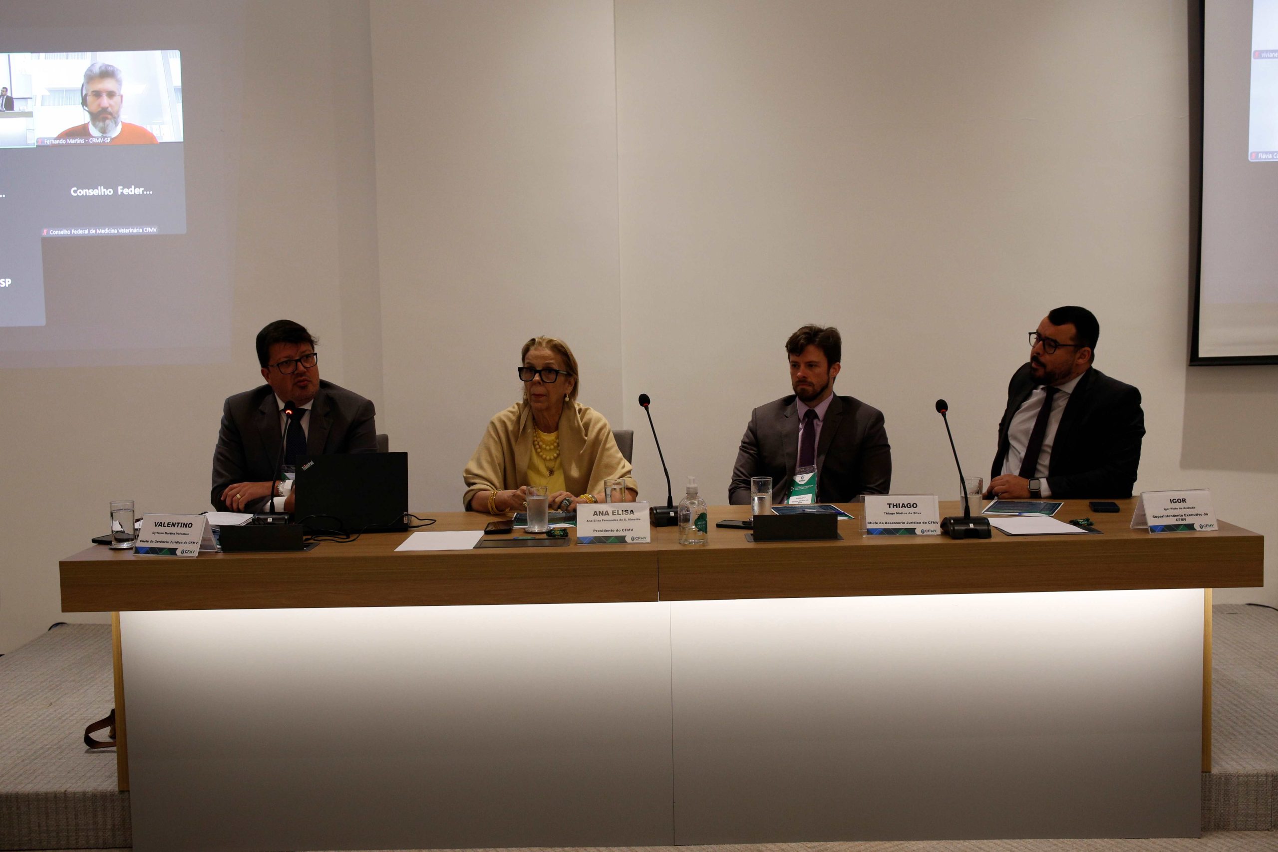 Quatro autoridades sentadas atrás de uma mesa em um palco em evento no CFMV.