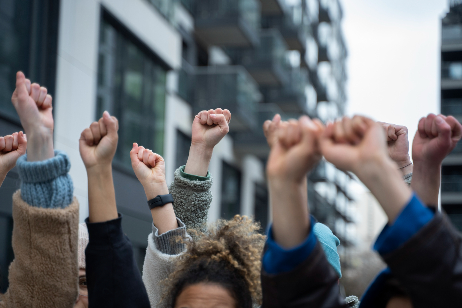 Várias mãos levantadas com o punho fechado dando a entender que as pessoas estão em uma manifestação.