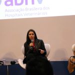 Mulher falando ao microfone frente ao telão. É a vice-presidente do CRMV-SP, Carolina Filippos.