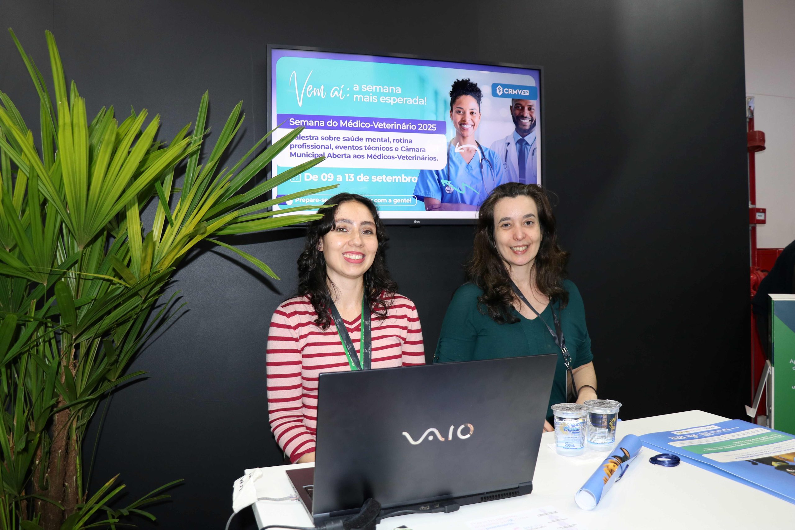 Mulheres juntas frente a um notebook posando para foto.
