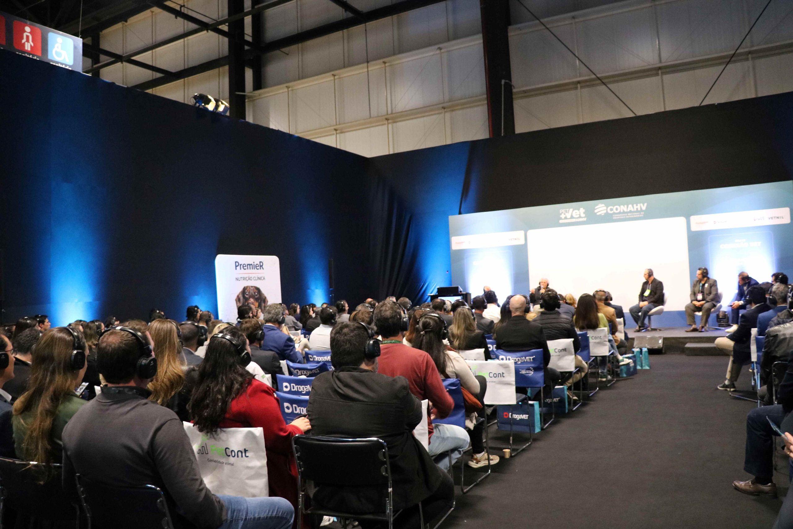 Pessoas sentadas de frente olhando para o telão.
