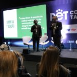 Dois homens em pé em cima do palco durante lançamento do Prêmio CFMV/CRMVs de Jornalismo.