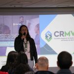 Na foto há uma mulher loira, frente ao telão, falando no microfone. É a presidente do CRMV-SP, Daniela Pontes Chiebao.