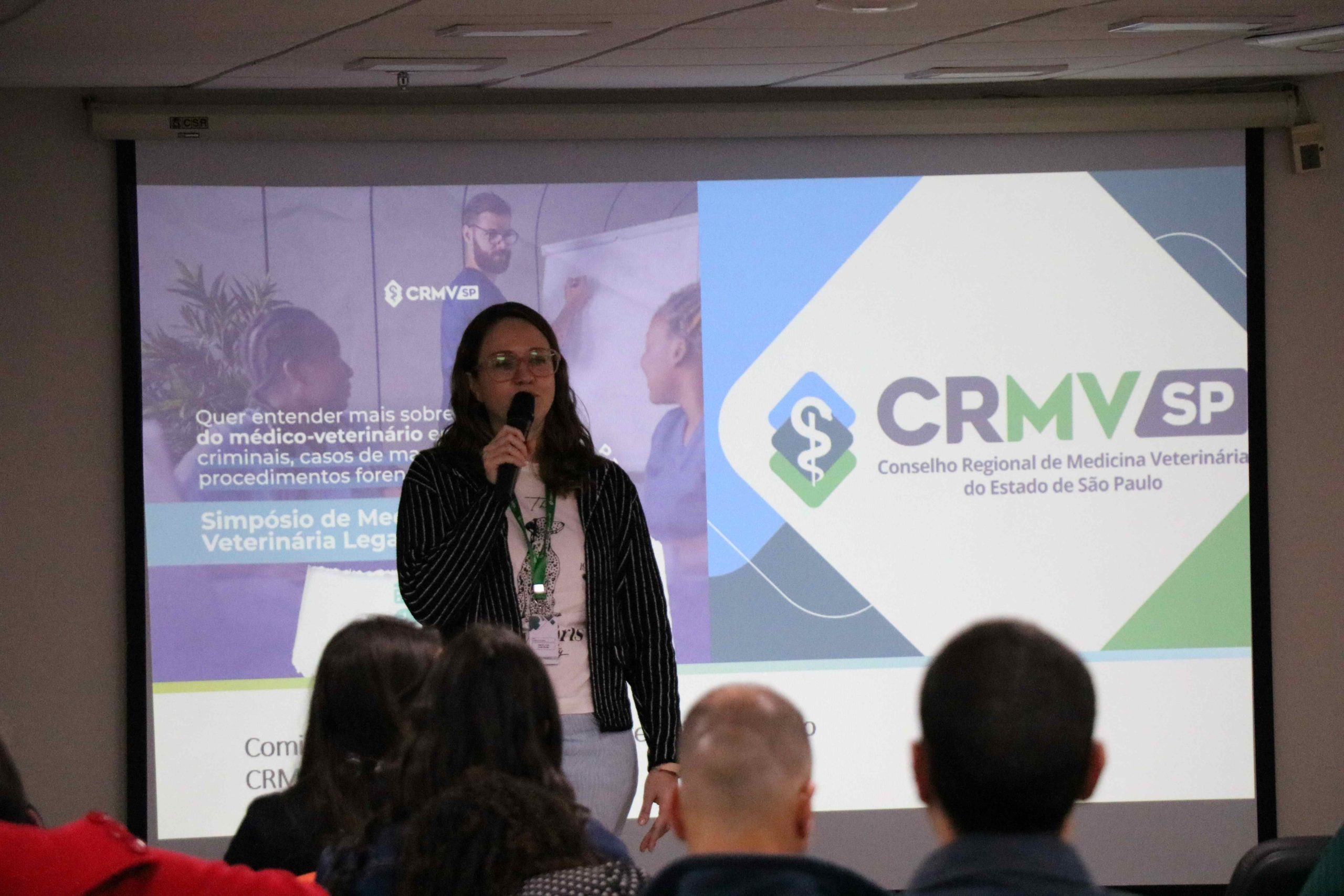 Na foto há uma mulher loira, frente ao telão, falando no microfone. É a presidente do CRMV-SP, Daniela Pontes Chiebao.