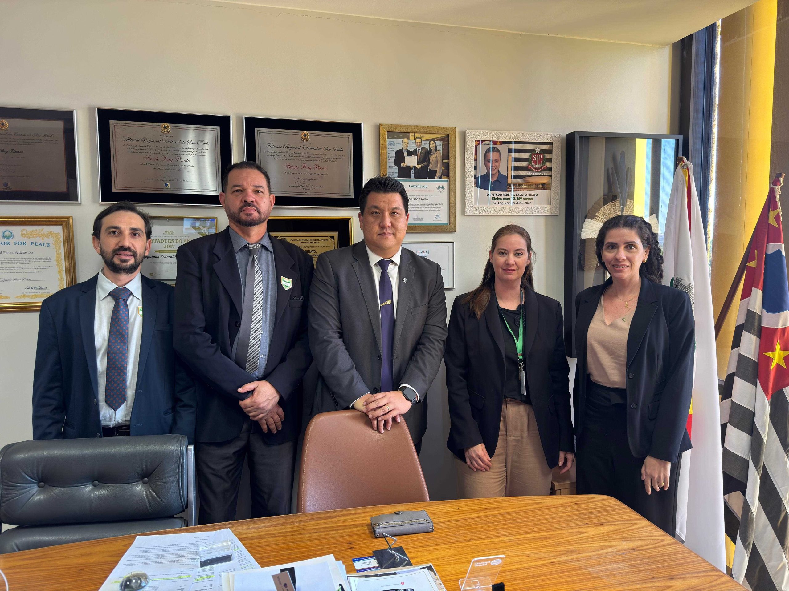 Cinco pessoas, três homens e duas mulheres, reunidas para fotografia.