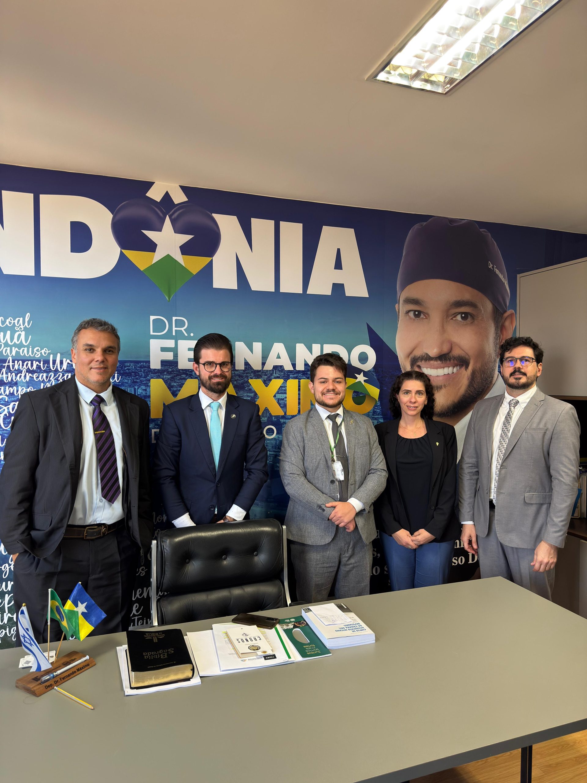 Pessoas reunidas para fotografia frente a mesa.
