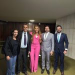 Cinco pessoas, duas mulheres e três homens, em pé pousando para fotografia.