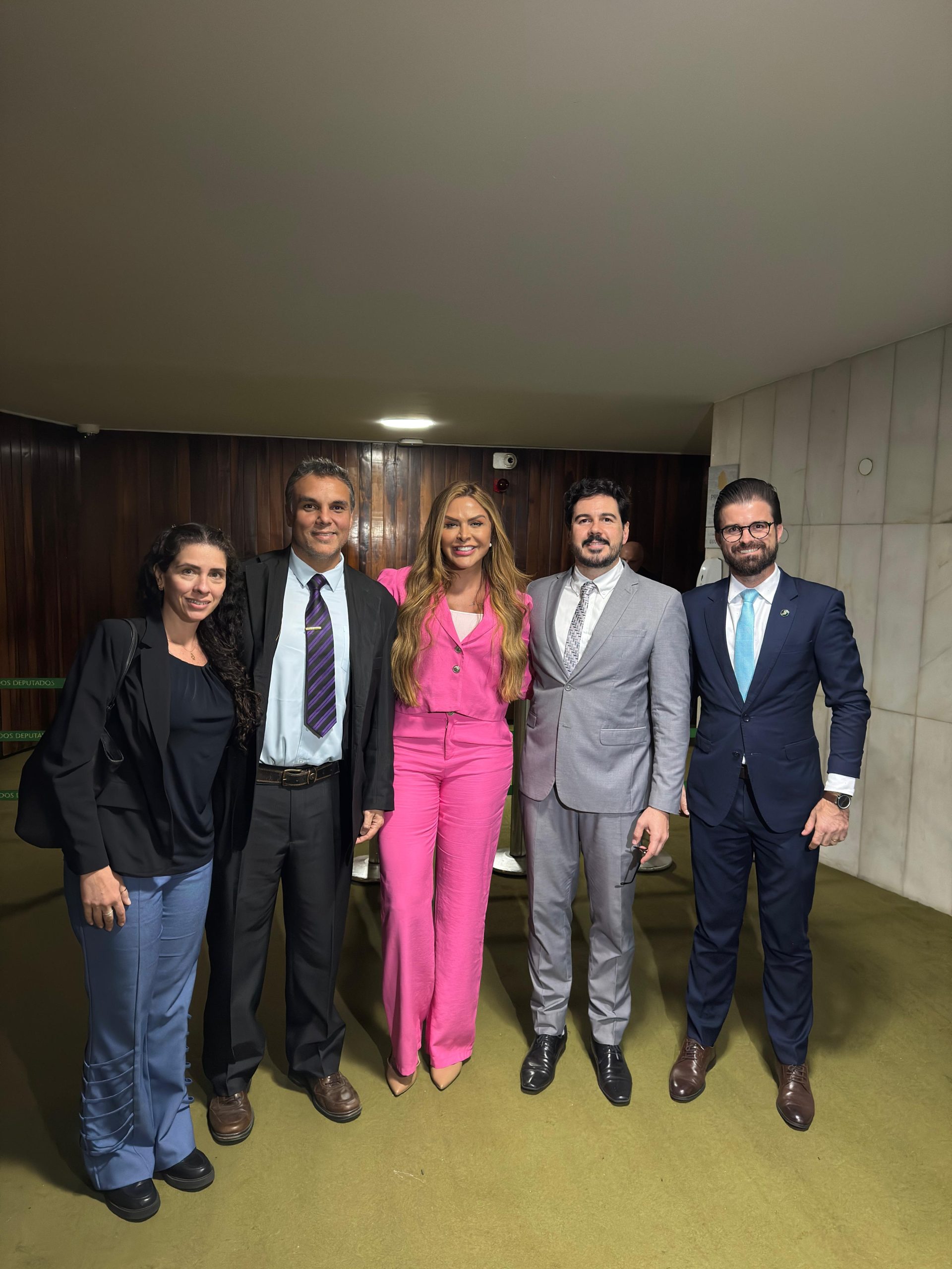 Cinco pessoas, duas mulheres e três homens, em pé pousando para fotografia.