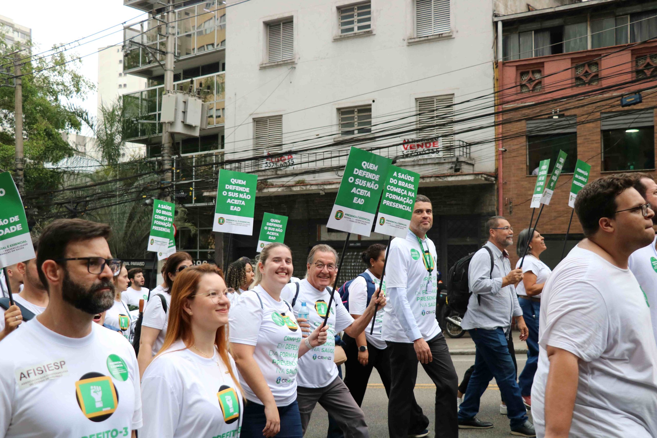Pessoas vestindo blusas brancas com dizeres contra o Ead subindo a avenida Brigadeiro Luís Antônio. Na imagem é possível ver os conselheiros do CRMV-SP, Daniela Denadai, Haroldo Alberti, e o diretor técnico Leonardo Burlini.
