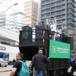 Carro de som preto à frente dos manifestantes na Avenida Brigadeiro Luís Antônio. Em cima do carro de som, a presidente do Fcafs-SP, Juliana Mendes.