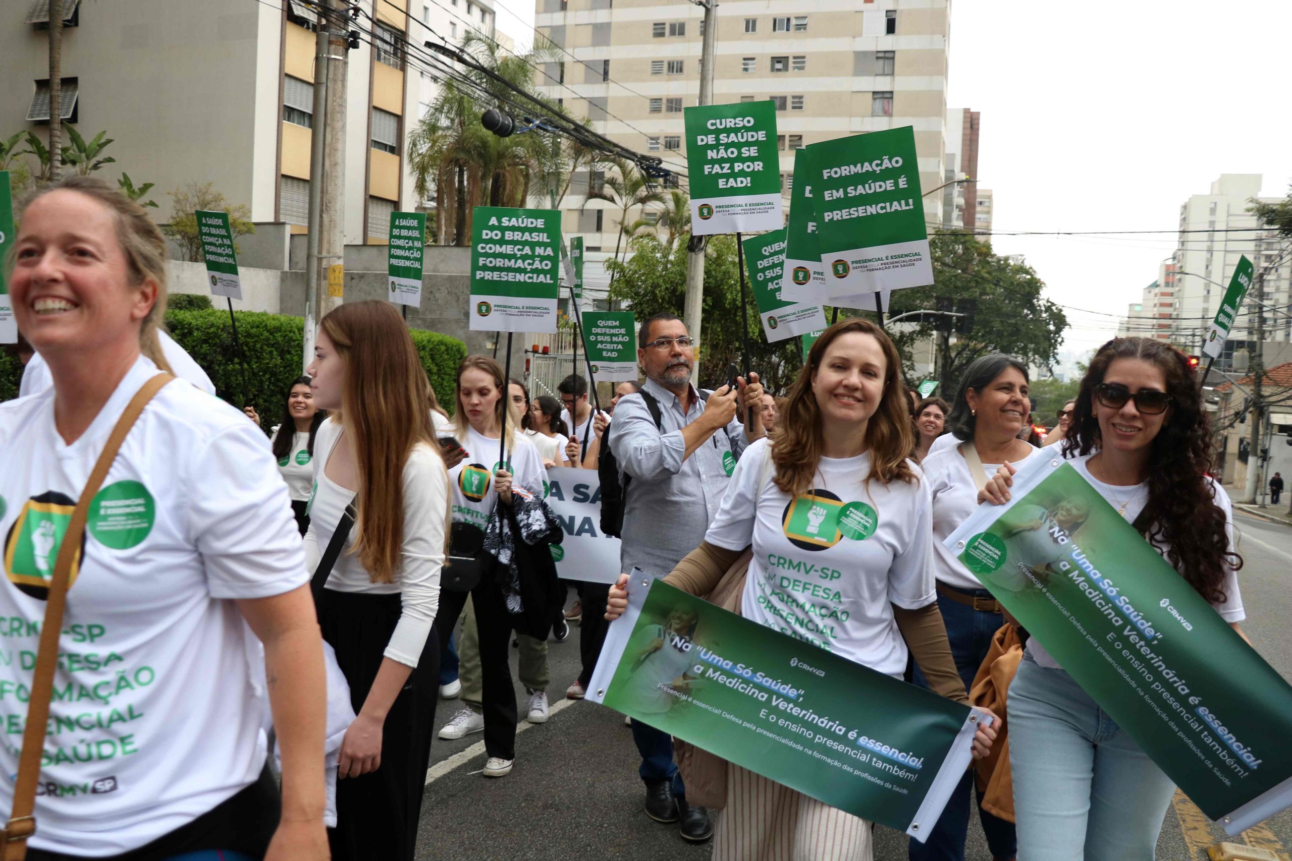 Na imagem é possível ver, da esquerda para a direita, a conselheira Alessandra Gonzales, a presidente do CRMV-SP Daniela Pontes Chiebao e ao lado direito dela, a vice-presidente Carolina Filippos, segurando faixas na cor verde com frases em letras brancas em defesa do ensino presencial.