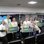 Pessoas em pé, homens e mulheres, vestindo blusa branca pousando para foto.