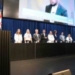 Pessoas em pé no palco preto pousando para foto.