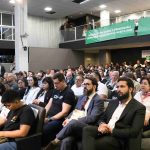 Pessoas sentada em um auditório.