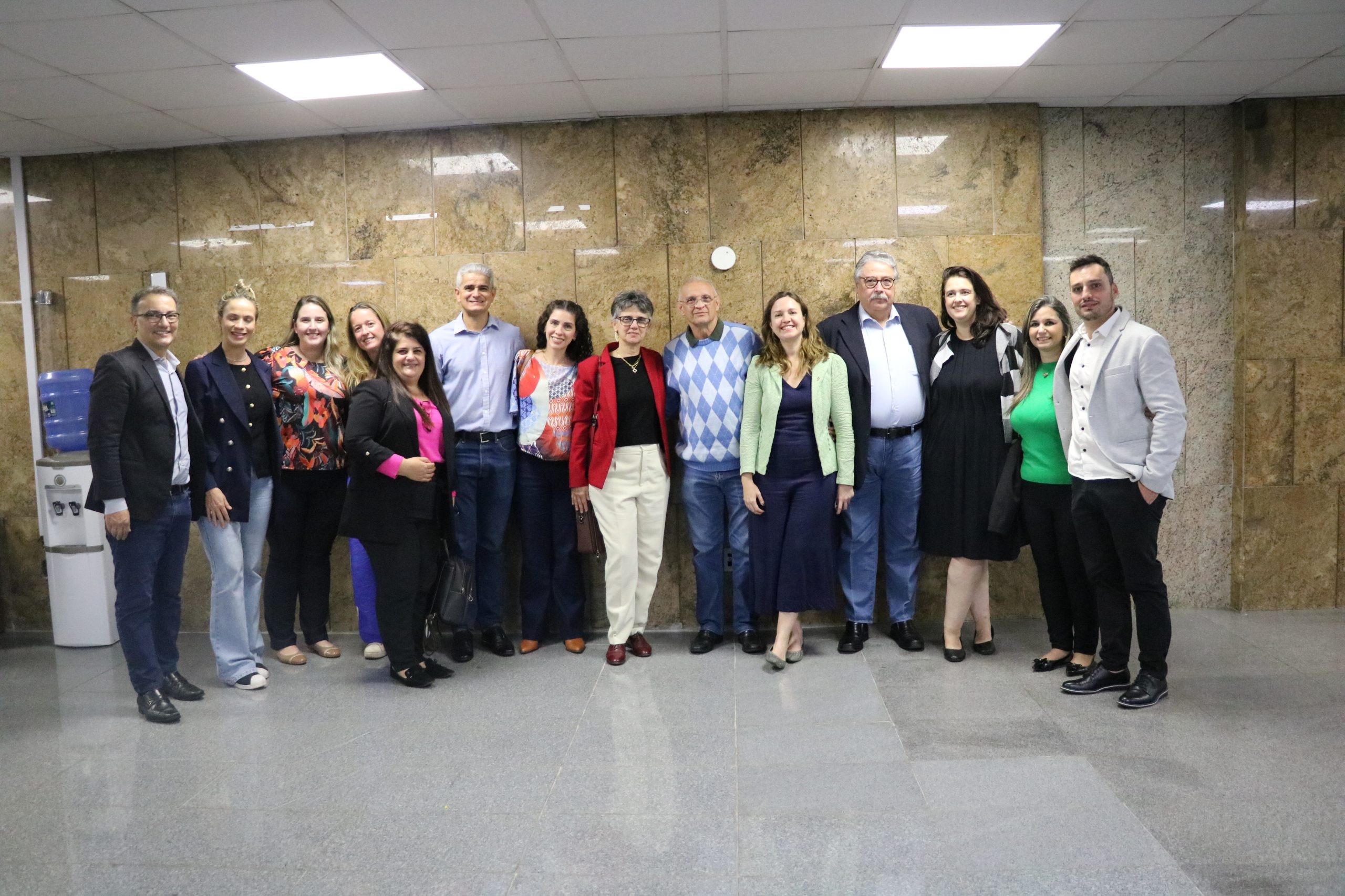 Imagem mostra 14 pessoas em pé pousando para foto no corredor da Alesp.