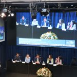 Visão a partir do mezanino das autoridades sentadas em em auditório oficial na Alesp. Da esquerda para a direita: Em pé no púlpito, a coordenadora técnica médica-veterinária do CRMV-SP, Carla Maria Figueiredo de Carvalho e sentados: o secretário-geral do CRMV-SP, Rodrigo Mainardi, a presidente da Comissão de Atenção à Saúde Mental dos Médicos-veterinários e Zootecnistas do CFMV, Ingrid Machado, o secretário de Desenvolvimento Econômico e Trabalho da Prefeitura de São Paulo, Rodrigo Goulart, a presidente do CRMV-SP, Daniela Pontes Chiebao e a vice-presidente do CRMV-SP, Carolina Filippos.