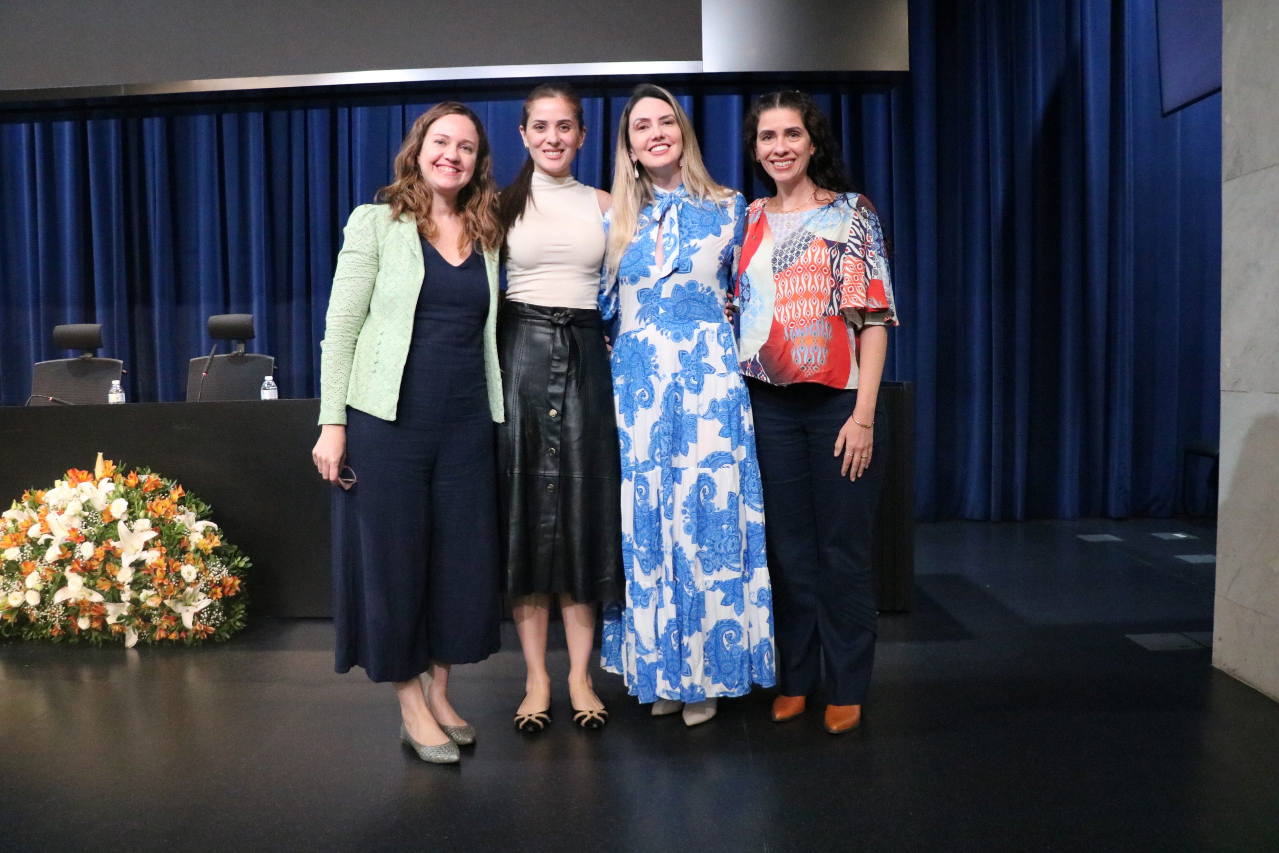 Quatro mulheres em pé pousando para foto em cima de um palco em auditório na Alesp. Da esquerda para a direita: a presidente do CRMV-SP, Daniela Pontes Chiebao, a psicóloga Bianca Stevanin Gresele, a presidente da Comissão de Atenção à Saúde Mental dos Médicos-veterinários e Zootecnistas do CFMV, Ingrid Bueno Atayde Machado e a vice-presidente do CRMV-SP, Carolina Filippos.