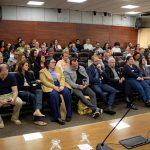 Pessoas sentadas em uma sala na Câmara Municipal observando uma palestra.