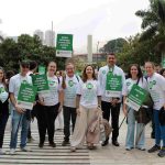 Pessoas em pé pousando para foto com placas em defesa do Ensino Presencial.