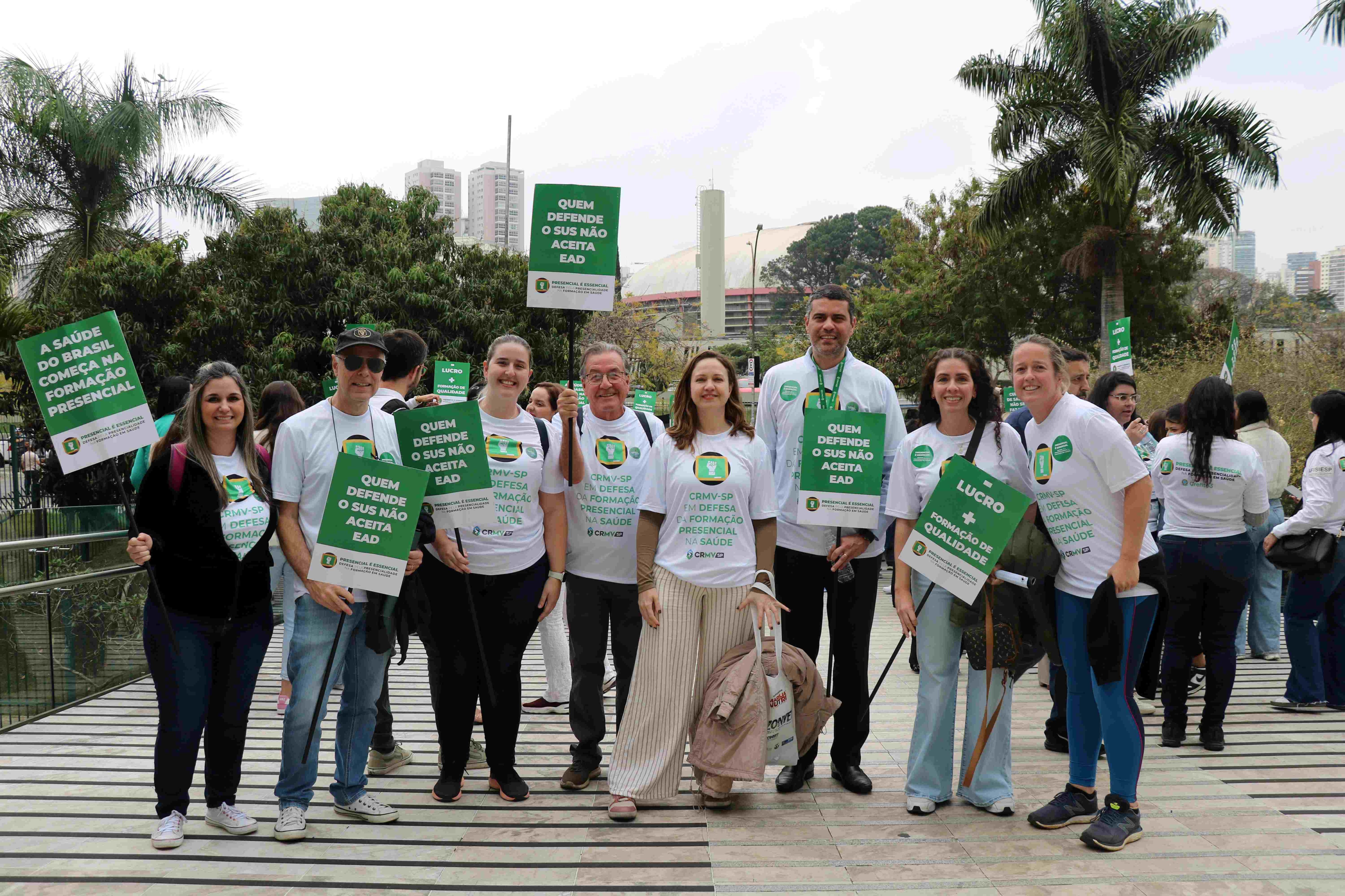 Pessoas em pé pousando para foto com placas em defesa do Ensino Presencial.