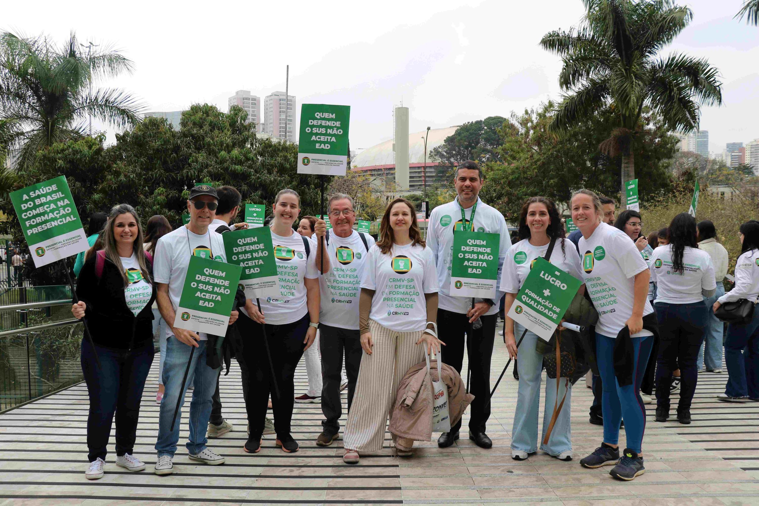 Pessoas em pé pousando para foto com placas em defesa do Ensino Presencial.