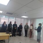imagem de pessoas em pé dentro de uma sala, uma delas com uma lembrança na mão.