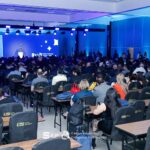 Pessoas sentadas frente ao palco.