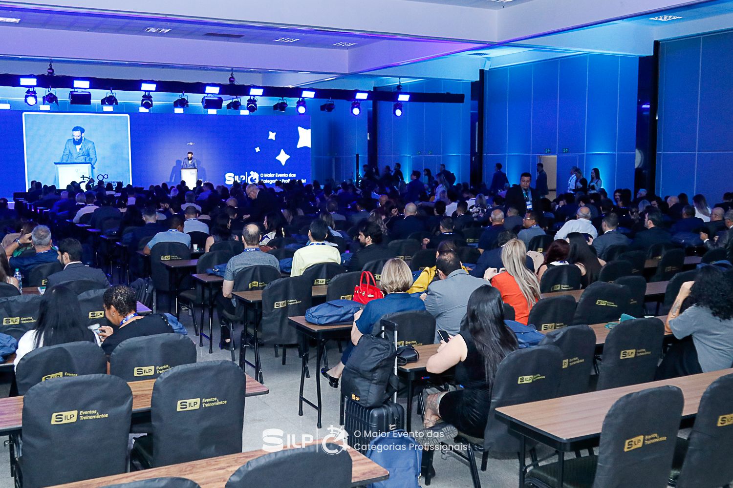 Pessoas sentadas frente ao palco.