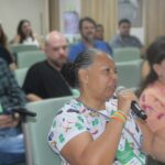 Mulher sentada falando no microfone.